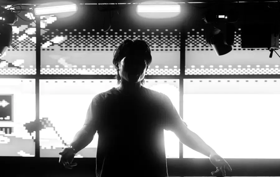 NAGA arms wide behind the decks, LED wall lit behind him