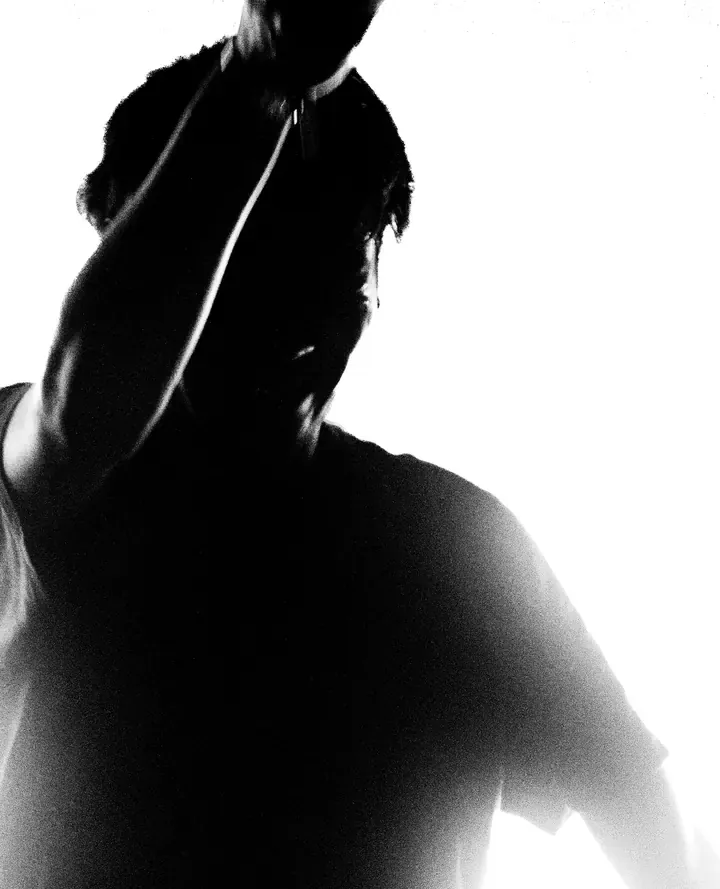 Studio portrait, hand raised against a blown-out backlight